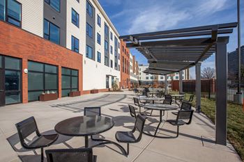 an outdoor patio with tables and chairs at a building with windows